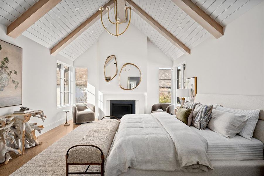 Designed for both comfort and style, the primary bedroom features a charming sitting area nestled beside a gas fireplace with a custom plaster surround, creating a cozy retreat within the space. Large windows flood the room with natural light, offering tranquil views of the surrounding landscape.