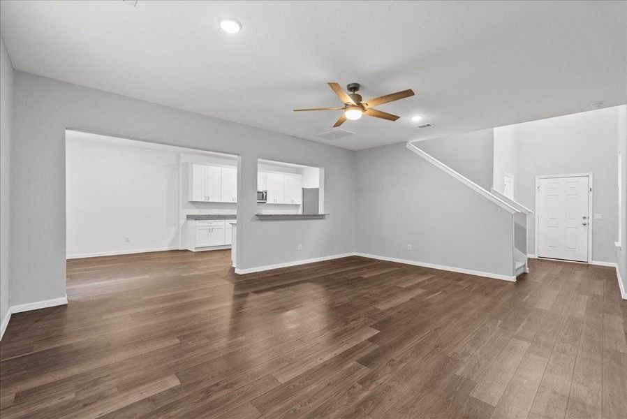 Another view of living room showing the dining room, kitchen, and entry way.