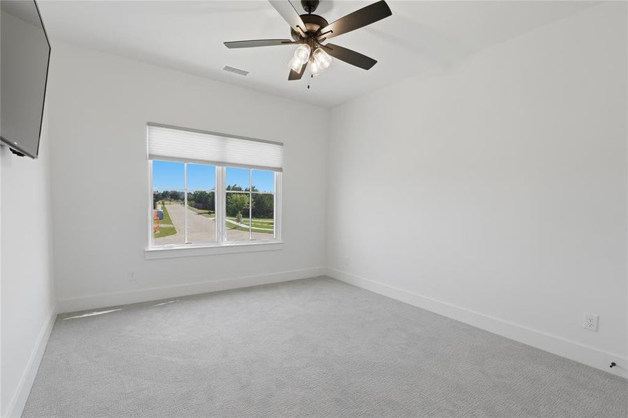 Spacious room featuring light gray carpeting, crisp white walls, and a large window with white blinds