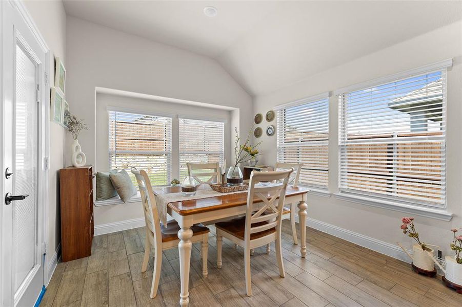 Dining space featuring plenty of natural light, lofted ceiling, and light wood-style floors Dining space featuring plenty of natural light, lofted ceiling, and light wood-style floors
