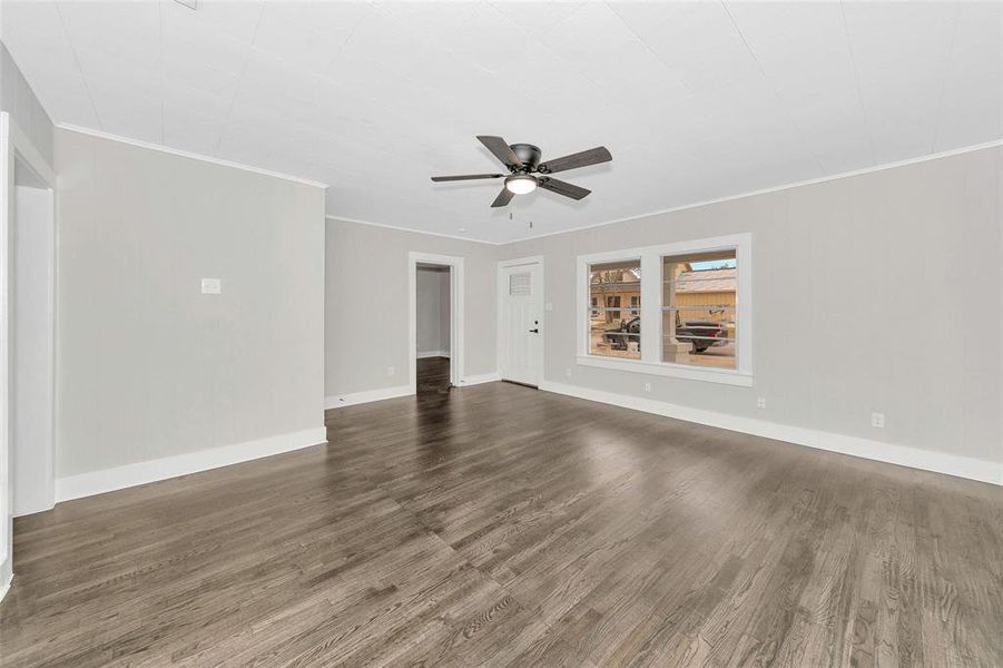 Unfurnished living room featuring dark wood finished floors, ceiling fan, and crown molding Unfurnished living room featuring dark wood finished floors, ceiling fan, and crown molding