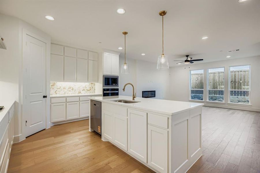 Kitchen with a center island with sink, light wood finished floors, white cabinetry, decorative backsplash, and recessed lighting Kitchen with a center island with sink, light wood finished floors, white cabinetry, decorative backsplash, and recessed lighting