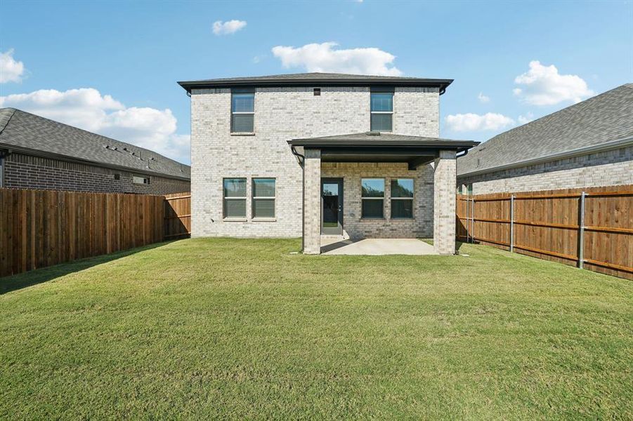 Rear view of house featuring brick siding, a patio area, and a fenced backyard