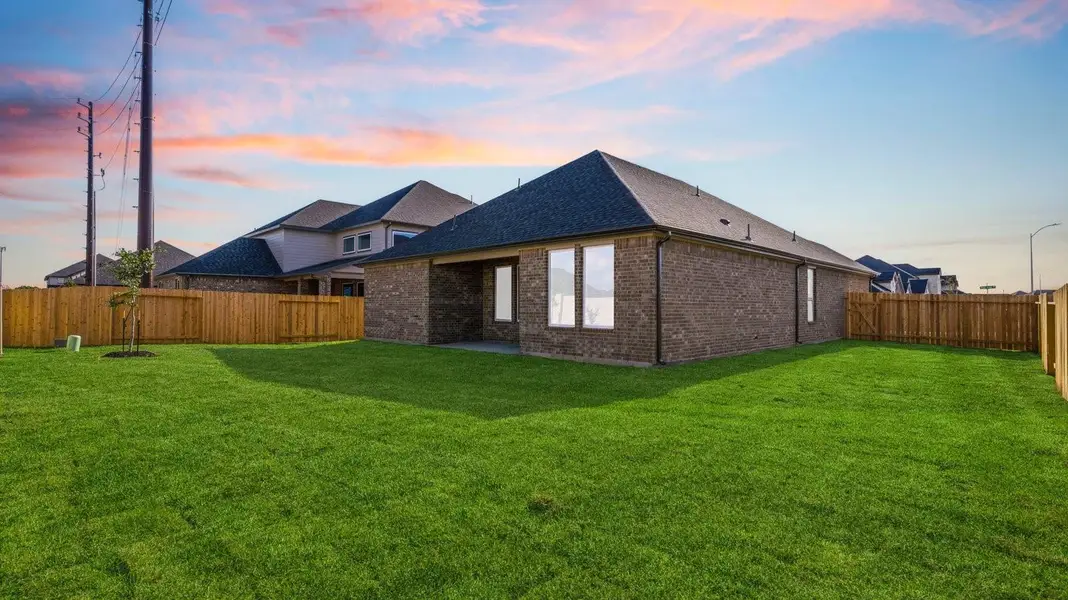 Large fenced-in backyard shown at night with a covered patio, perfect for outdoor entertaining. Large fenced-in backyard shown at night with a covered patio, perfect for outdoor entertaining.