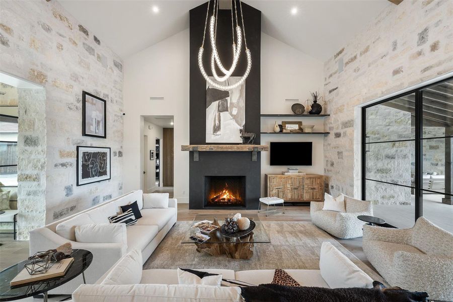 Optional To Be Built -  A grand living space with a vaulted ceiling and a stately stone fireplace creates a luxurious atmosphere.