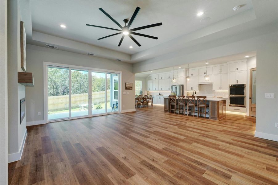 Open-concept interior featuring wood-finish flooring, a contemporary ceiling fan, and recessed lighting