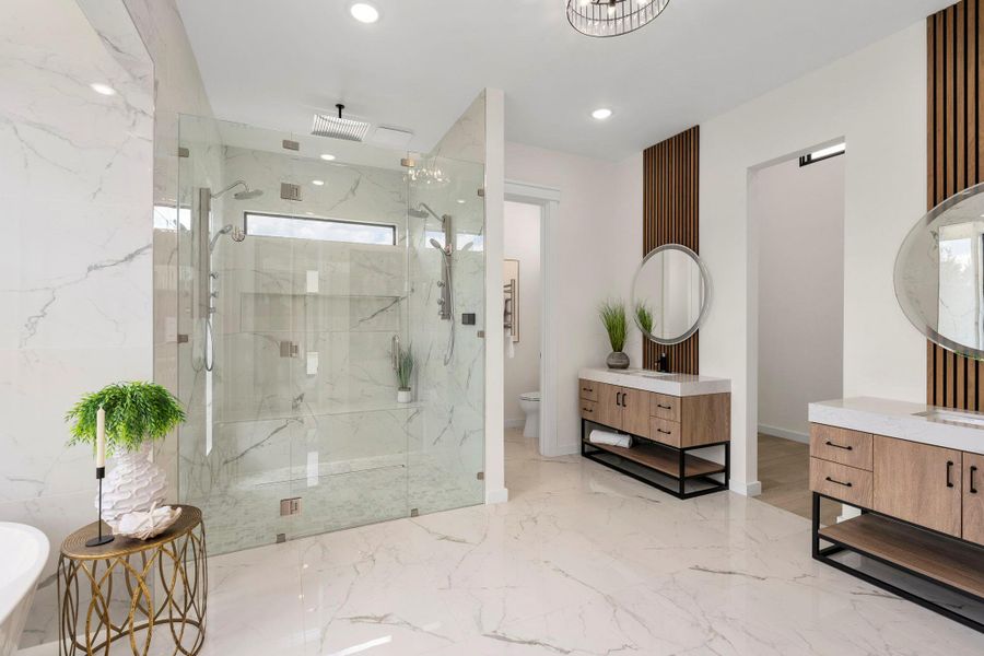 Full bath with a soaking tub, a marble finish shower, two vanities, recessed lighting, and light marble finish flooring