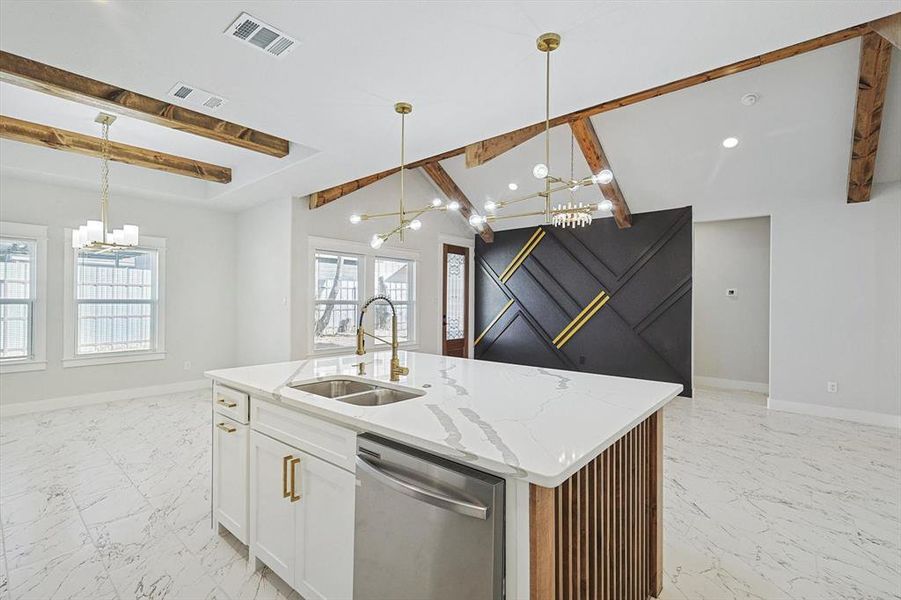 Kitchen with decorative light fixtures, dishwasher, sink, and a center island with sink