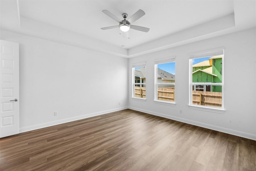 A well-lit bedroom features durable plank flooring and a modern ceiling fan.