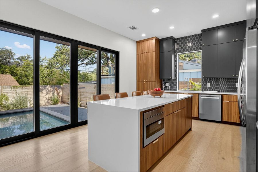 Kitchen with modern cabinets, a kitchen bar, light wood-style floors, and recessed lighting