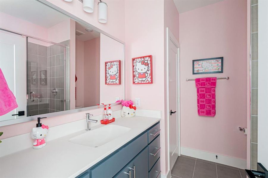 Full bathroom with vanity, dark tile patterned floors, and a shower stall