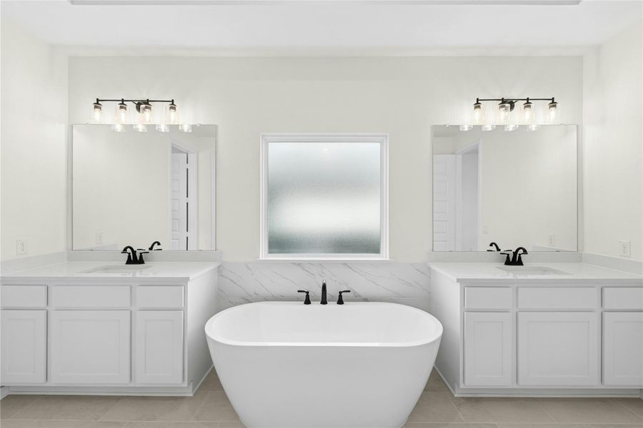 Full bathroom featuring two vanities, tile walls, a freestanding tub, a wainscoted wall, and light tile patterned flooring Full bathroom featuring two vanities, tile walls, a freestanding tub, a wainscoted wall, and light tile patterned flooring