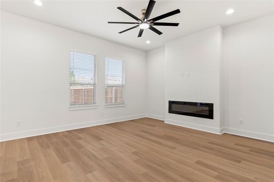Unfurnished living room featuring a glass covered fireplace, recessed lighting, light wood finished floors, and a ceiling fan Unfurnished living room featuring a glass covered fireplace, recessed lighting, light wood finished floors, and a ceiling fan