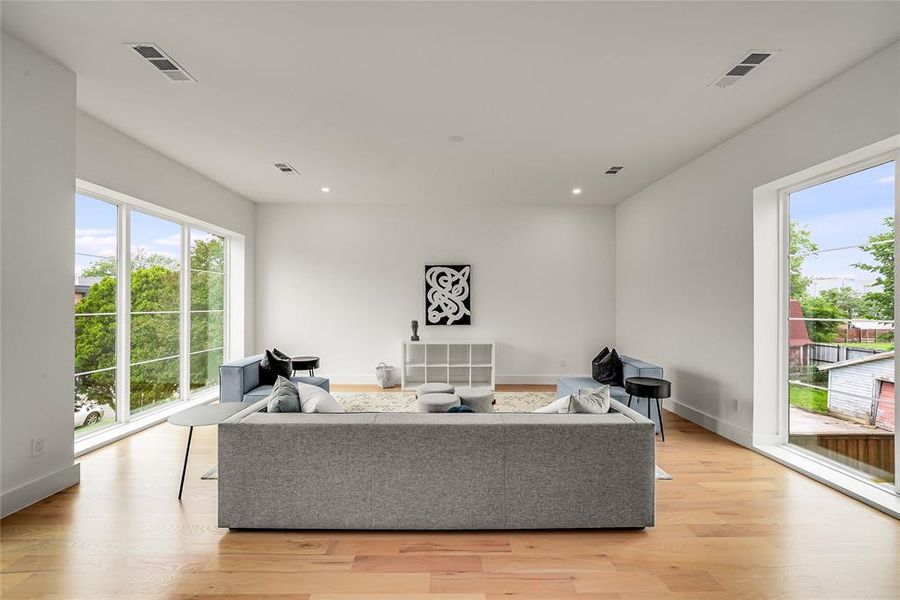 Spacious living area featuring expansive windows, recessed lighting, wood-finish flooring, white walls, and clean-line architecture