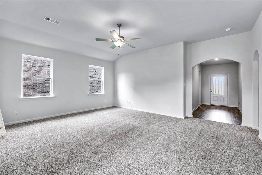 Spare room featuring dark colored carpet and ceiling fan