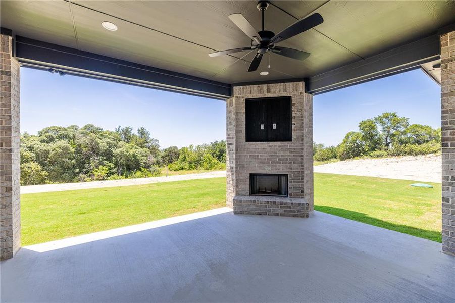 View of patio with an outdoor brick fireplace and ceiling fan