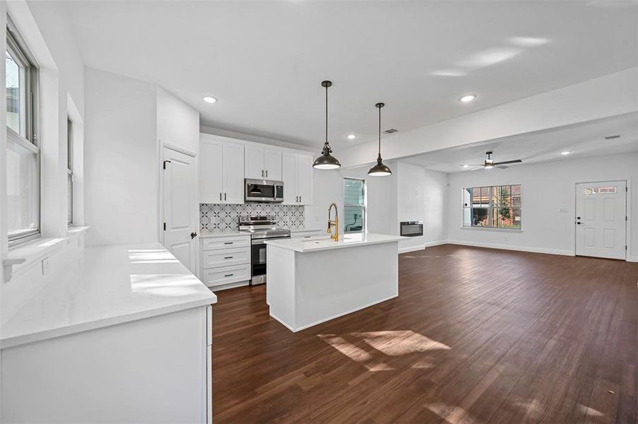 Kitchen featuring white cabinetry, plenty of natural light, decorative light fixtures, and appliances with stainless steel finishes