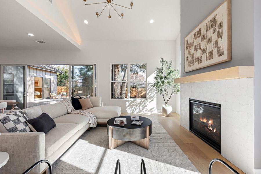 Living area featuring a chandelier, wood finished floors, a tile fireplace, and lofted ceiling