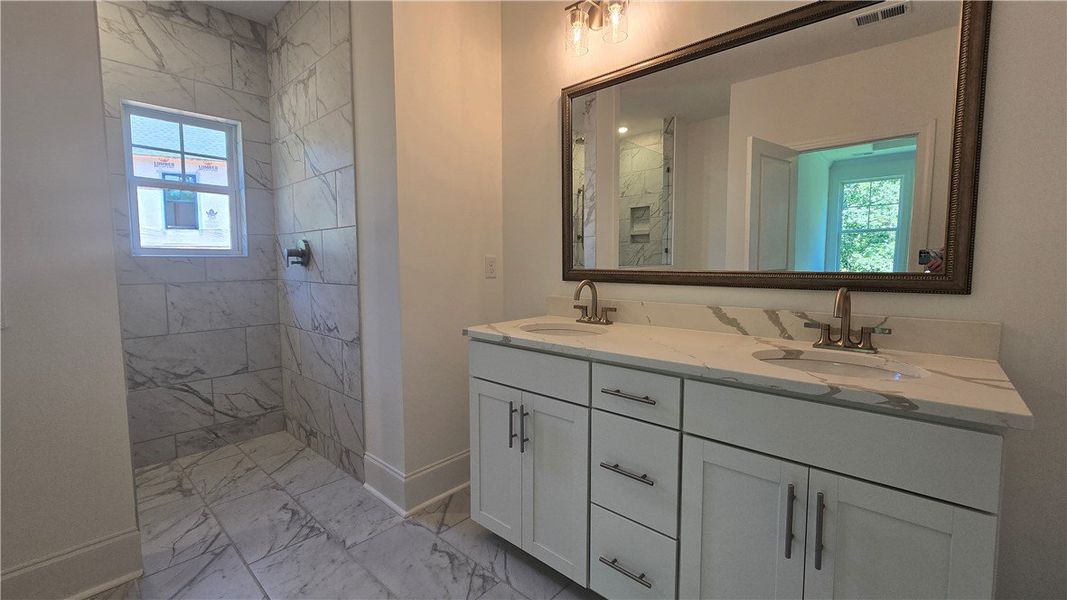 Ceramic-tiled shower and double vanity offer a ref