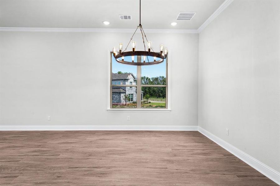 Dining area with modern chandelier, luxury vinyl flooring, large window for an abundance of natural lighting, crown molding, and recessed lighting. Dining area with modern chandelier, luxury vinyl flooring, large window for an abundance of natural lighting, crown molding, and recessed lighting.