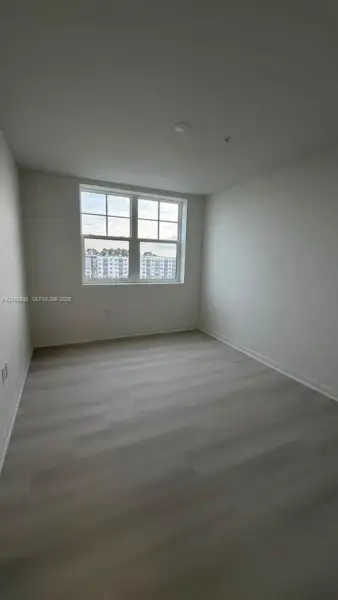 Neutral-toned wood-finish flooring, double-hung divided light window, and smooth-finish walls