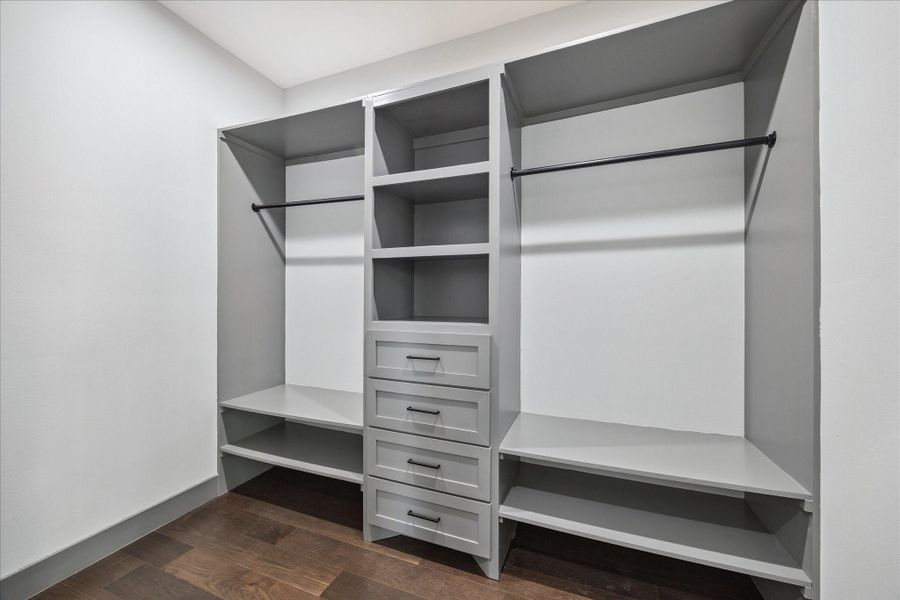 Organized living is made easy with a spacious walk-in closet featuring built-in shelving, drawers, and double hanging rods. The layout offers flexibility for clothing, shoes, and accessories, keeping everything within easy reach.