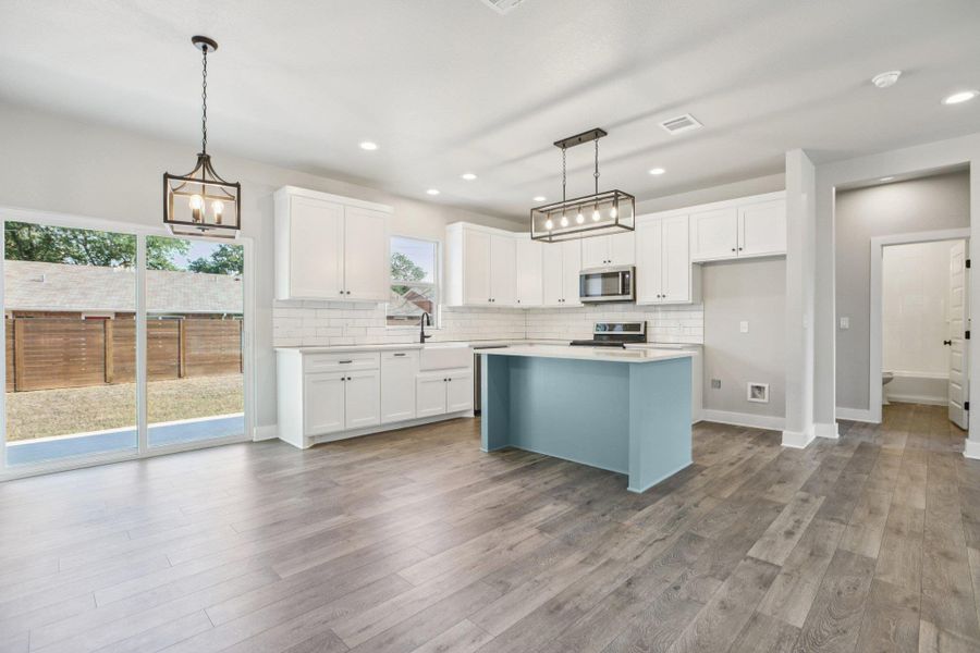 Kitchen with white cabinetry, hanging light fixtures, decorative backsplash, a kitchen island, and recessed lighting