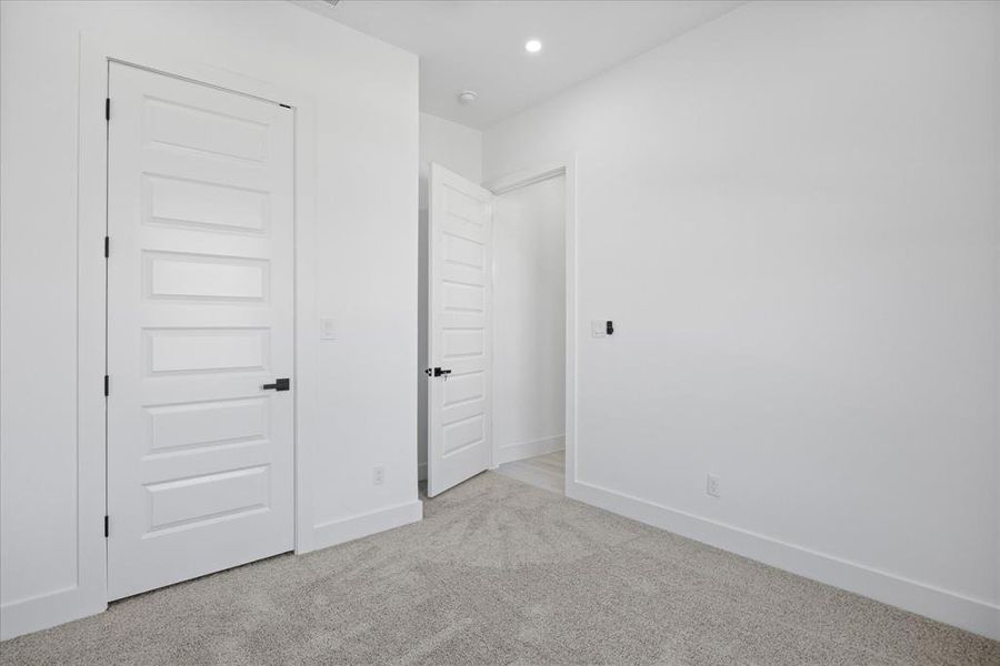 Kids/Guest bedroom featuring light gray carpeting, crisp white walls, recessed lighting, and modern five-panel doors with matte black hardware