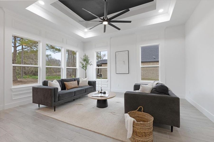 Living room featuring light wood-type flooring, a tray ceiling, crown molding, and recessed lighting