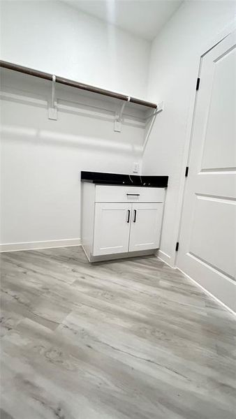 Walk in closet with light wood-type flooring