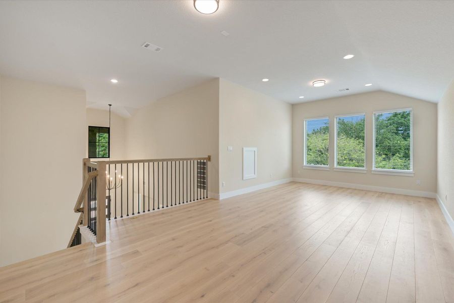 A generous loft space offers a peaceful escape, naturally illuminated by three windows overlooking lush greenery.