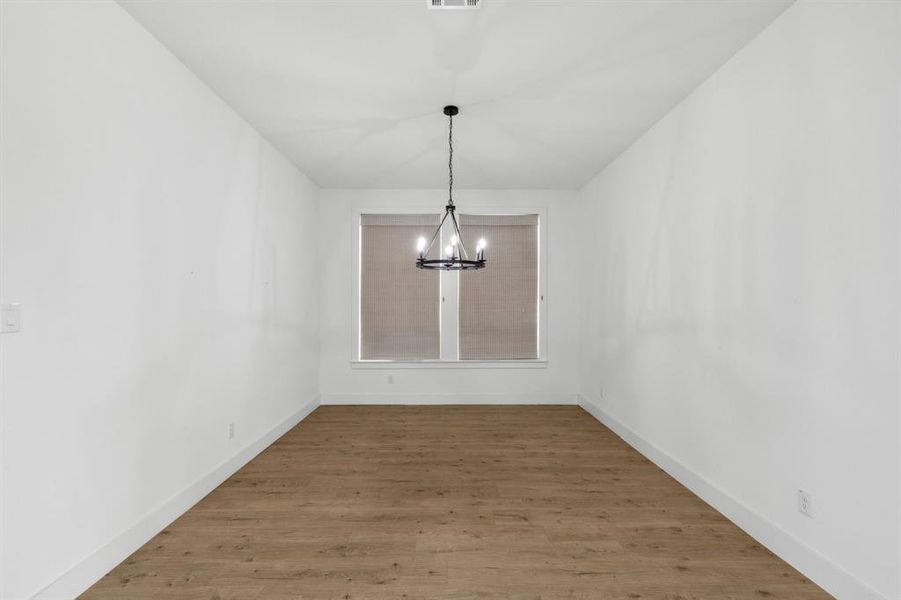 Unfurnished dining area featuring hardwood / wood-style flooring and a chandelier