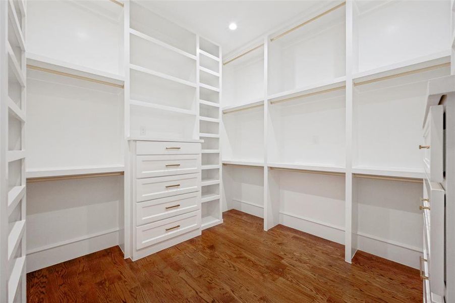 Built-in closet system featuring white cabinetry, multiple shelves, and integrated drawers with brass hardware