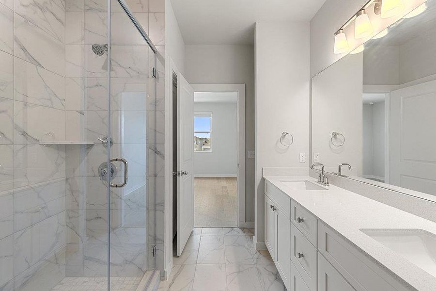 Full bath with a marble finish shower, double vanity, and light marble finish flooring