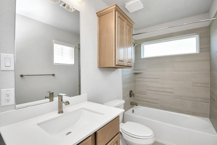 Secondary bath features tile flooring, bath/shower combo with tile surround, light stained wood cabinets, beautiful light countertop. Sample photo of completed home with similar floor plan. Actual colors and selections may vary. Secondary bath features tile flooring, bath/shower combo with tile surround, light stained wood cabinets, beautiful light countertop. Sample photo of completed home with similar floor plan. Actual colors and selections may vary.