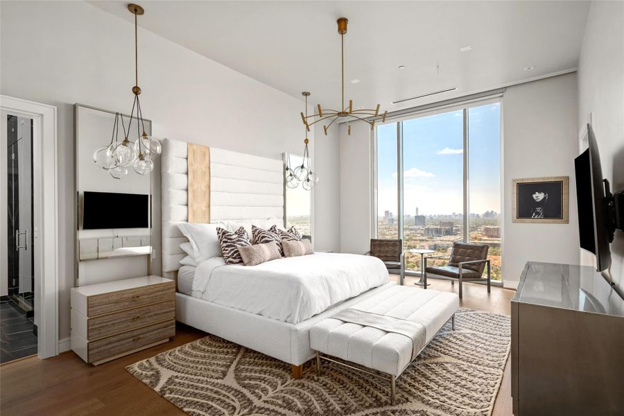 The primary retreat is a serene sanctuary with floor-to-ceiling windows that bathe the space in natural light and showcase stunning views. Luxurious light fixtures and elegant finishes create a sophisticated and inviting atmosphere perfect for relaxation.