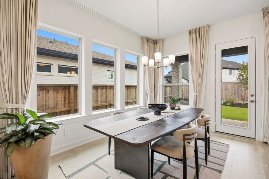 Bright and inviting dining area with large windows, stylish chandelier, and seamless access to the backyard, perfect for entertaining and enjoying natural light.