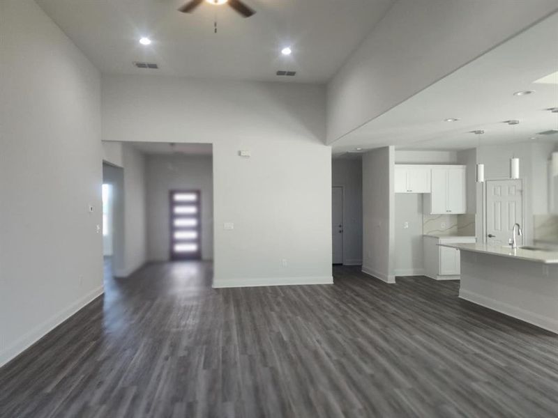 Unfurnished living room with a ceiling fan, dark wood-style flooring, recessed lighting, and a towering ceiling Unfurnished living room with a ceiling fan, dark wood-style flooring, recessed lighting, and a towering ceiling