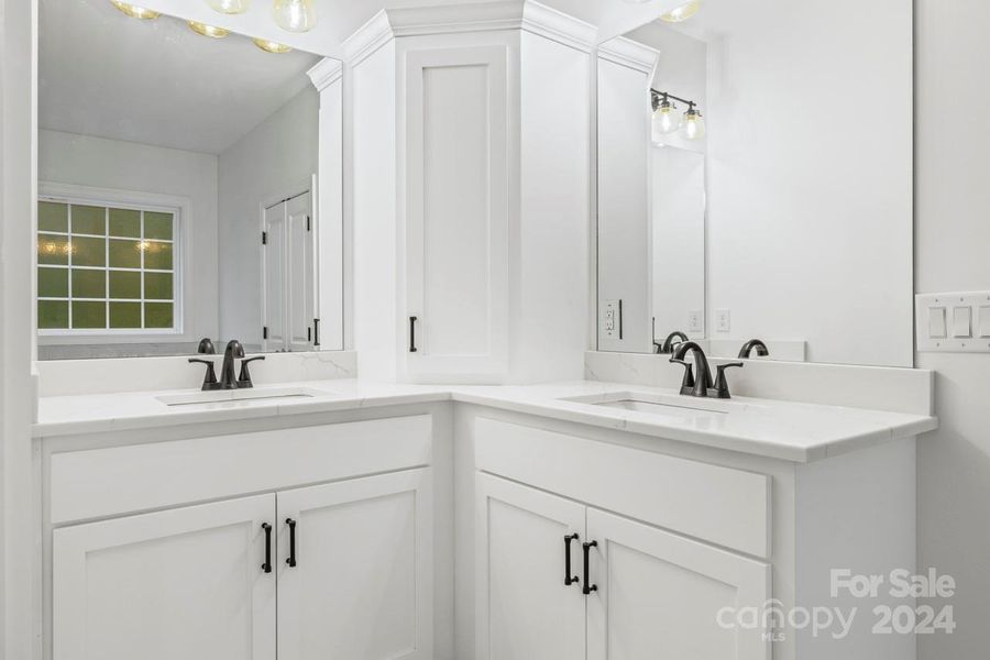 Two vanity areas and a custom corner cabinet are functional features here