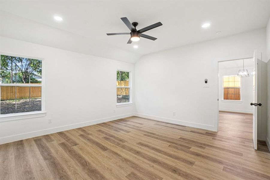 Empty room featuring recessed lighting, light wood-style flooring, lofted ceiling, and ceiling fan Empty room featuring recessed lighting, light wood-style flooring, lofted ceiling, and ceiling fan