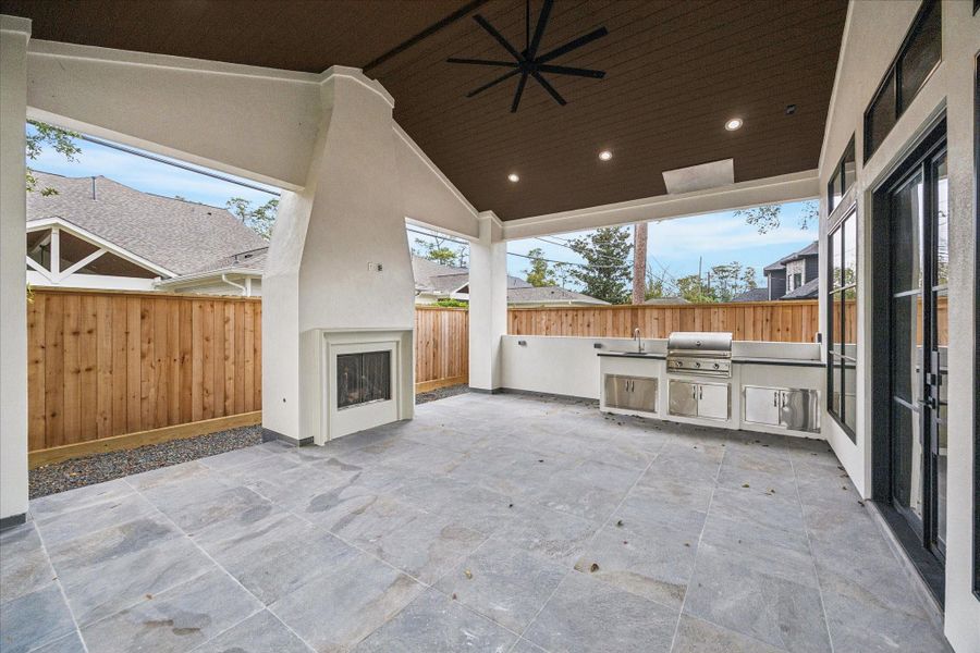 A modern stucco fireplace, V-groove wood ceiling, integrated lighting, and a full summer kitchen — including grill, sink, and storage — create an outdoor retreat crafted for year-round living. *Previous Project*
