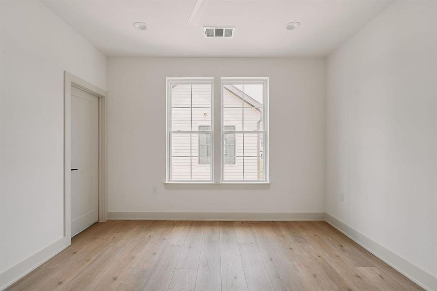 Room featuring light wood-finish flooring, white walls, and recessed lighting