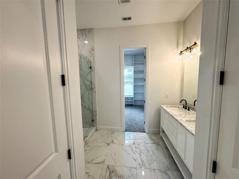 Full bathroom with marble finish flooring, a marble finish shower, baseboards, and double vanity Full bathroom with marble finish flooring, a marble finish shower, baseboards, and double vanity