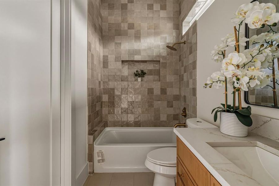 Full bath featuring washtub / shower combination, vanity, and light tile patterned floors