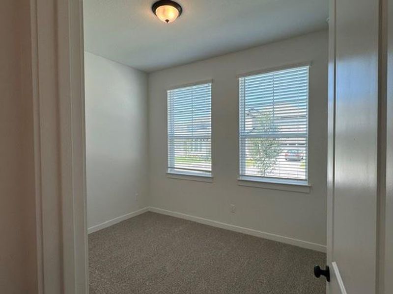 A quiet secondary bedroom offers comfortable carpeted flooring and natural light through two windows.