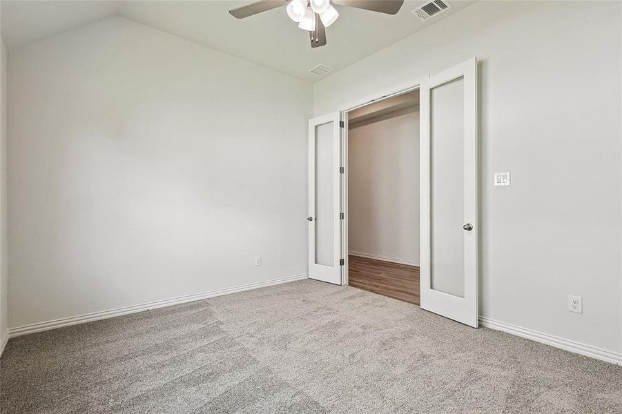 Unfurnished bedroom with lofted ceiling, a closet, carpet, and ceiling fan