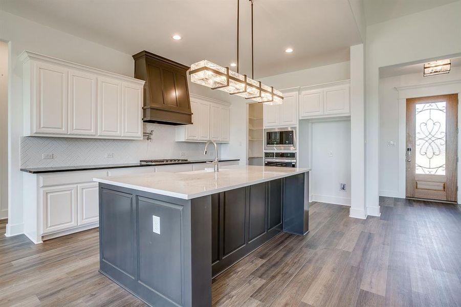 Two tone kitchen featuring dual tone cabinetry, dark stone counters, dark wood-style flooring, stainless steel appliances, and decorative backsplash Two tone kitchen featuring dual tone cabinetry, dark stone counters, dark wood-style flooring, stainless steel appliances, and decorative backsplash