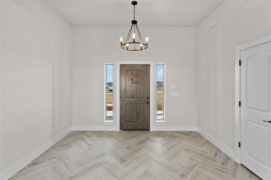 Entrance foyer featuring a chandelier and light parquet floors