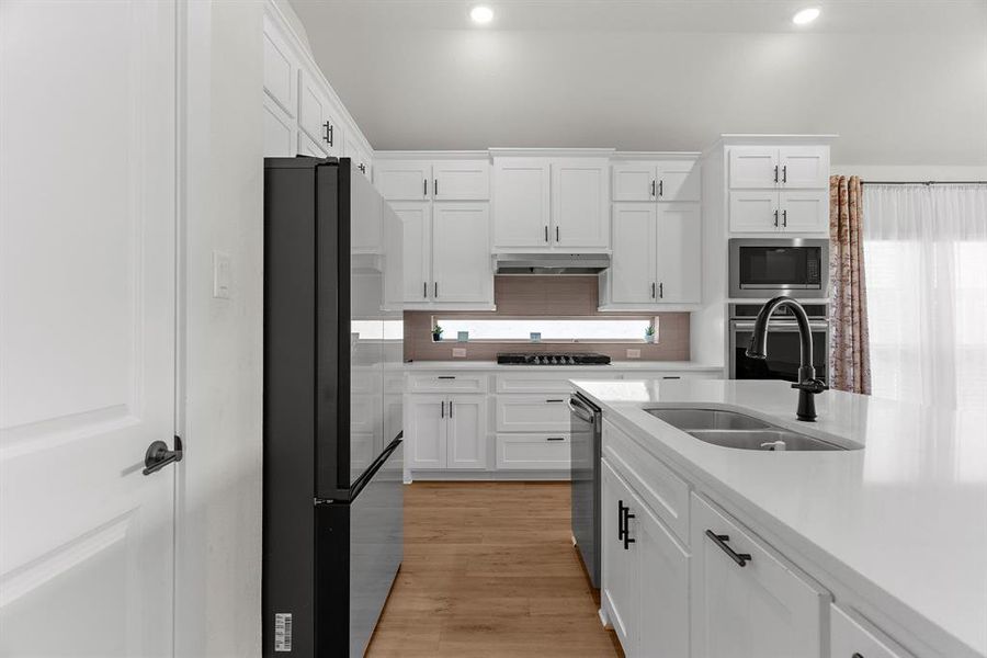 Kitchen with black appliances, a sink, white cabinetry, light countertops, and recessed lighting Kitchen with black appliances, a sink, white cabinetry, light countertops, and recessed lighting