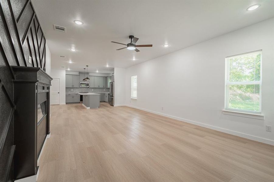 Unfurnished living room featuring a ceiling fan, light wood-style floors, recessed lighting, and a glass covered fireplace Unfurnished living room featuring a ceiling fan, light wood-style floors, recessed lighting, and a glass covered fireplace